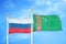 Russia and Turkmenistan two flags on flagpoles and blue cloudy sky