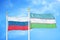 Russia and Uzbekistan two flags on flagpoles and blue cloudy sky