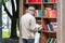 Russia, Vladivostok, 07/06/2019. A man stands by the wooden street cabinet with free books. Books in the cabinet are free, anyone