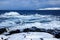 Russian Arctic View, North. Sky with clouds and blue sky reflection in water with waves and snow mountains background with stones