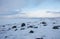 Russian Arctic View, North. Sky with clouds and blue sky reflection in water with waves and snow mountains background with stones