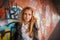 Russian beautiful smiling teenager girl with long blond hair and make up near the wall graffiti, selective focus