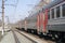 Russian electric train in red, orange, gray. Railway, poles with wires