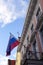 Russian flag, bottom up view to yellow and pink buildings facades. Weather vane on the roof. Blue sky with white clouds