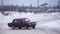 Russian maroon car `VAZ Zhiguli` goes fast sideways in winter turning the wheel and raising snow on the turn of the road