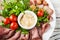 Russian national cuisine. Marinated tomatoes, chopped meat, olives, parsley. Horseradish sauce. Salad closeup on a plate.