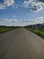 Russian outback, view of the outgoing road, blue sky and green meadows in Kamen-na-Obi, Altai, Russia. Vertical