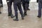 Russian police officers legs in black ankle boots, red stripe pants and with rubber tonfa night sticks.