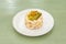 Russian salad top with pickled gherkins on white plate
