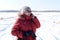 Russian senior woman talking on phone against snowy field. winter