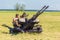 A Russian soldier sits on a zu-23-2 anti-aircraft gun, ready for defense on a sunny summer day