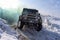 Russian SUV `UAZ hunter 469` 4x4 goes fast, turning tires on a difficult road in the snow in winter in colored smoke.