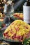 Russian Traditional New Year salad herring under fur coat - shuba in plate on dark table served with glasses, bottle of wine,