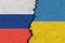 Russian and Ukrainian flags on a cracked concrete wall