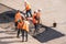 Russian workers in orange uniform closing up a hole in asphalt using shovels