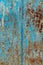 Rust and damaged blue and yellow paint on metal sheet