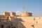 Rustaq castle with an Omani flag on a sunny day.