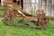 Rusted abandoned vintage agricultural farming equipment used to work with tractors on soil left in high grass in front of metal