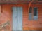 Rusted blue front door and window over orange facade. Tropical construction. Martinique, Antilles. French West Indies