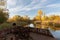 rusted boat sitting next to river surrounded by trees with golden leaves