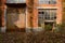 Rusted door and broken windows of deserted 1970s` red brick workshop