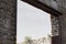 Rusted metal framework in open archway of wall with stones and brick, open sky behind