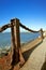 Rusted metal post and chain fence by bay