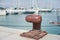 Rusted mooring bollard with sailing boat in background