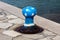 Rusted old iron mooring bollard shaped and painted like blue mushroom with white spots mounted on traditional stone pier