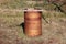 Rusted old metal oil barrel used as large garbage can for weeds and old plants with cracked wooden board and stone tile on top