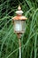 Rusted vintage retro garden lantern candle holder with battery powered candle placed in local garden surrounded with dense plants