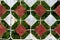 Rusted vintage retro top of metal fence driveway doors with white and dark red decorative tiles on green grass background