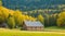 A rustic barn nestled among tall trees at the edge of a village