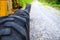 Rustic black tire of tractor and road perspective view. Heavy machinery detail in outdoor landscape. Road construction