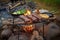 rustic campfire grilling setup with lamb chops and veggies