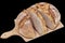 Rustic Coarse Crusty Monastery Bread Sliced On Wooden Cutting Board Isolated On Black Background