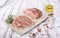 Rustic composition with raw meat, pork loin in cross-section and in chops, on a white plate, on white vintage boards.