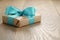 Rustic craft paper gift box with blue ribbon bow on wood table
