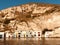 Rustic, cute houses jut out of the bottom of a rock formation in Milos - GREECE - MILOS