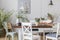 Rustic dining room with long table and white chairs and oil painting on the grey wall, real photo