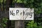 Rustic handmade do it yourself No Parking sign on a worn wooden fence