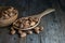 On a rustic hardwood floor, almonds in a wooden ladle and a wooden bowl