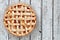 Rustic homemade peach pie, above view on aged white wood