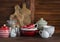 Rustic kitchen still life. Olive cutting board, jar of flour, bowls, pan, enamelled jar, gravy boat. On a dark brown wooden ta