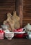 Rustic kitchen still life. Olive cutting board, jar of flour, bowls, pan, enamelled jar, gravy boat. On a dark brown wooden ta