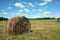 Rustic landscape with summer field with many rolled haystacks with one of it close-up