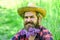 Rustic man with beard happy face enjoy life in ecological environment. Hipster with lilac flowers looks happy. Bearded