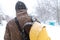 A rustic man is walking down the street in winter with a yellow backpack. Snow blizzard