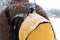 A rustic man is walking down the street in winter with a yellow backpack. Snow blizzard