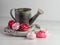 Rustic metal watering can with gray wooden wreath and light and dark pink paper roses on a sandstone and white background